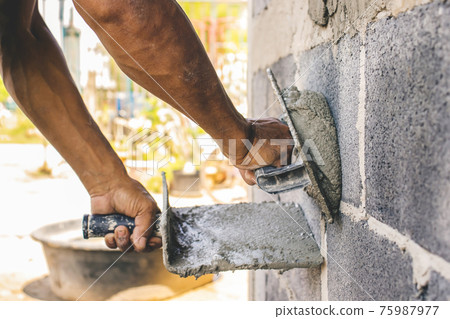 Close-up of workers using plaster trowel to plaster the walls for house construction, working ideas and residential construction. 75987977
