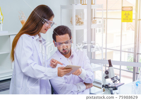Doctor and microbiologist with vacuum tubes for samples with COVID 19 infection atypical pneumonia virus in laboratory Doctor and microbiologist with vacuum tubes for samples with COVID 19 infection atypical pneumonia virus in laboratory 75988629