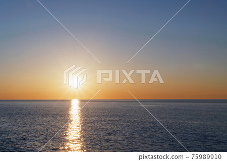 The setting sun goes into the sea on the horizon with a light track and reflections on the sea. The setting sun goes into the sea on the horizon with a light track and reflections on the sea. 75989910