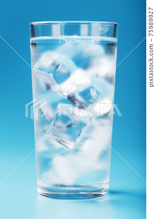 A glass with ice and clean water on a blue background. A glass with ice and clean water on a blue background. 75989927