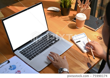 Close up view of female accountant calculating and working on laptop computer at workplace. 75990174