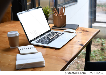 Comfortable workplace with computer laptop, notebook, coffee cup and pencil holder on wooden table. Comfortable workplace with computer laptop, notebook, coffee cup and pencil holder on wooden table. 75990232