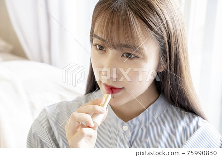A woman applying lipstick 75990830