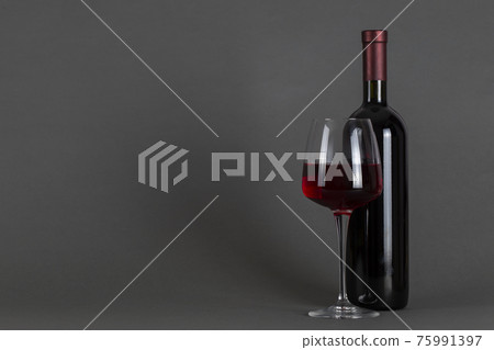 Red wine bottle and glass on a gray background. Wine drinking culture concept. Red wine bottle and glass on a gray background. Wine drinking culture concept. 75991397