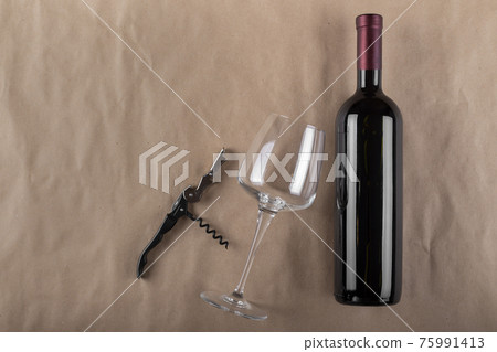 Wine bottle, glass and corkscrew on a brown background. Space for text. 75991413