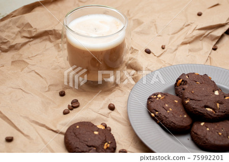 Chocolate chip cookies and coffee in double glass on craft paper 75992201