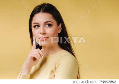 Portrait of amazing lady with makeup. Empty space deep thinking, arm on chin wear casual yelow sweeter isolated yellow color background. Closeup. Place for text 75992608