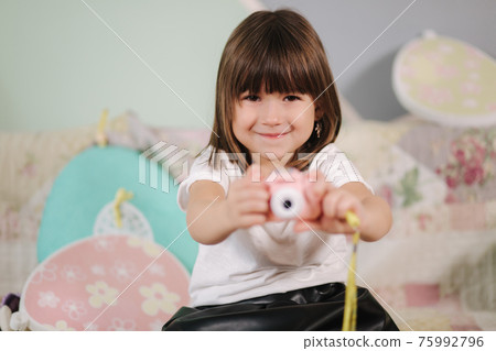 Young girl photographer make photo of her toy camera. Cute little girl play at home Young girl photographer make photo of her toy camera. Cute little girl play at home 75992796