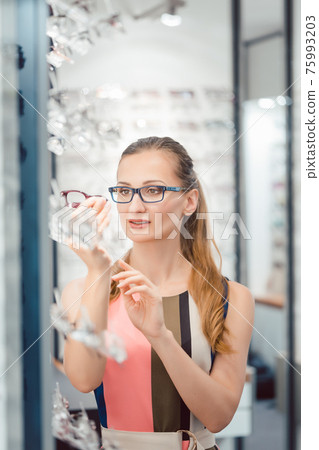 Woman being satisfied with the new eyeglasses she bought in the store 75993203