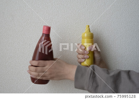 Hand with ketchup and mustard 75995128