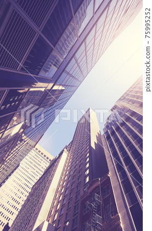 Looking up at New York skyscrapers against the sun, color toned picture, USA. 75995252