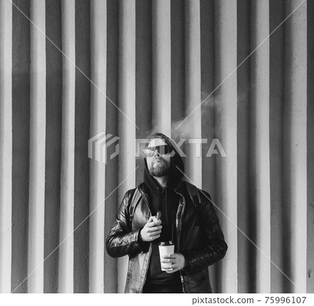 handsome young bearded guy in vaping an electronic cigarette 75996107