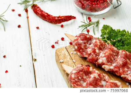 Raw lula kebab on skewers with spices on wooden board 75997068