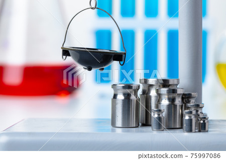 Laboratory scales with weights against test tubes Laboratory scales with weights against test tubes 75997086