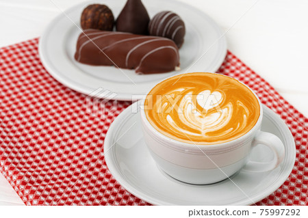 Cup of coffee and saucer with chocolate sweets on wooden table Cup of coffee and saucer with chocolate sweets on wooden table 75997292