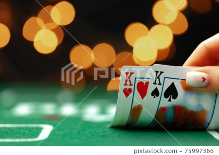 Female hand holding playing cards against bokeh background 75997366