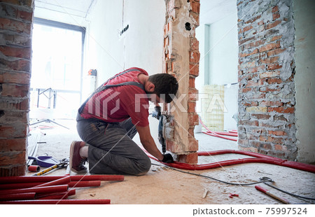 Male worker installing heating system in apartment. 75997524