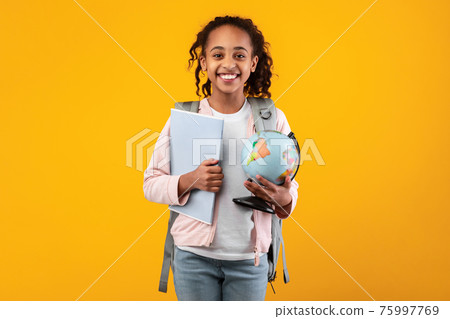 Cheerful young black girl holding Earth world globe and notebook 75997769