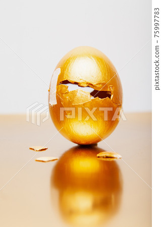 Golden egg with triangle hole placed on reflective table Golden egg with triangle hole placed on reflective table 75997783