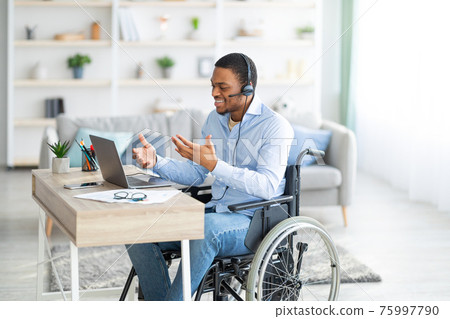 Disabled black guy with headset communicating online on laptop, having business meeting from home Disabled black guy with headset communicating online on laptop, having business meeting from home 75997790