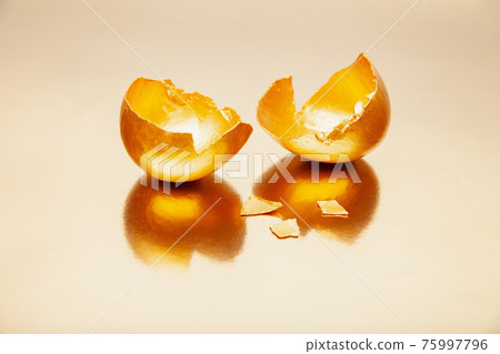 Golden eggshell placed on surface on reflective table 75997796