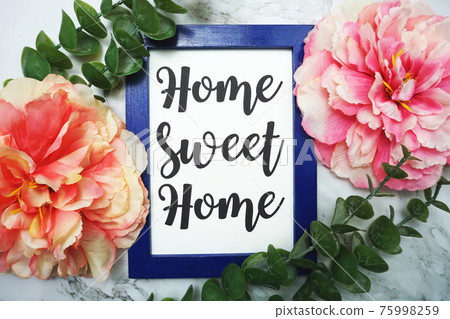 Home Sweet Home written on blue frame with green leave and pink flower flat lay on marble background Home Sweet Home written on blue frame with green leave and pink flower flat lay on marble background 75998259