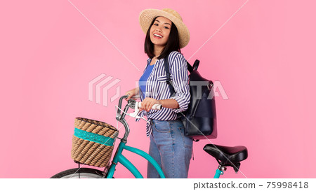 Smiling asian woman standing with retro bicycle with wicker basket Smiling asian woman standing with retro bicycle with wicker basket 75998418
