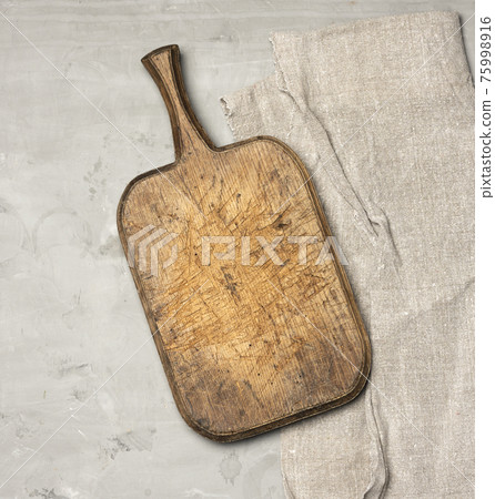 very old brown wooden kitchen cutting board and gray linen napkin on the table very old brown wooden kitchen cutting board and gray linen napkin on the table 75998916