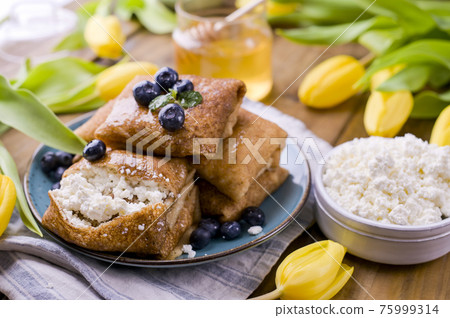 Large traditional Russian pancakes with berries and honey on a wooden table. Baking for the spring Large traditional Russian pancakes with berries and honey on a wooden table. Baking for the spring 75999314