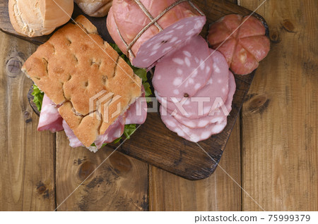 Big Italian Mortadella. Lunch from Focaccia with rosemary with mortadela and green salad 75999379