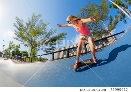 Young woman riding on surf skate Young woman riding on surf skate 75999412