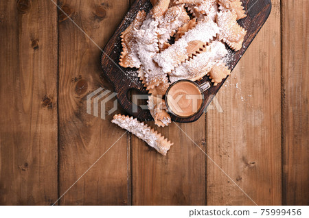 Carnival food TYPICAL and aromatic coffee on a woody background view from above. Sfrappole or 75999456