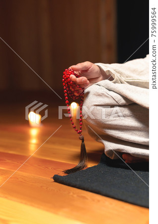 close-up, a man with a rosary in his hand sits in a room by candlelight 75999564