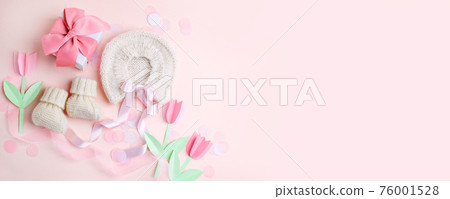Pair of small baby socks, bonnet, gift box on pink background with copy space for your warm message, baby shower, first newborn party background, copy space, monochrome, banner 76001528