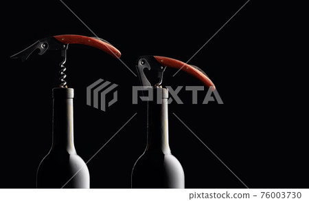 Bottles of wine with corkscrews on a black background. Bottles of wine with corkscrews on a black background. 76003730