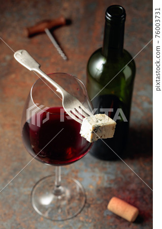 Blue cheese on a fork and red wine. Blue cheese on a fork and red wine. 76003731