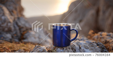 Closeup photo of cup with tea over out of focus mountains view. 76004164