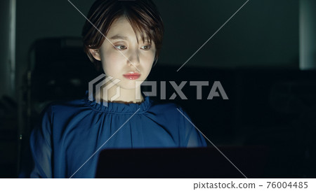 一位女士在黑暗的辦公室使用 PC 76004485