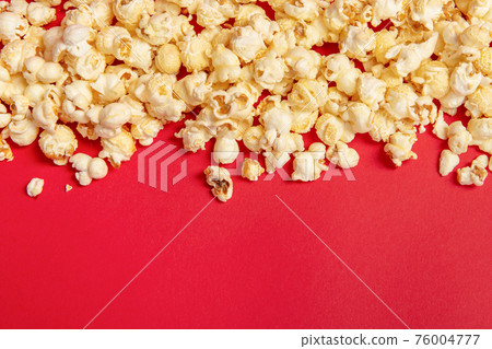Popcorn on a red background as a concept for movies with space for copy 76004777