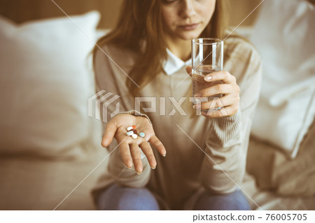 Close-up woman holding pills time to take medications, cure for headache, high blood pressure or cholesterol level remedy pain killer drugs. Stay at home concept during Coronavirus pandemic and self Close-up woman holding pills time to take medications, cure for headache, high blood pressure or cholesterol level remedy pain killer drugs. Stay at home concept during Coronavirus pandemic and self 76005705