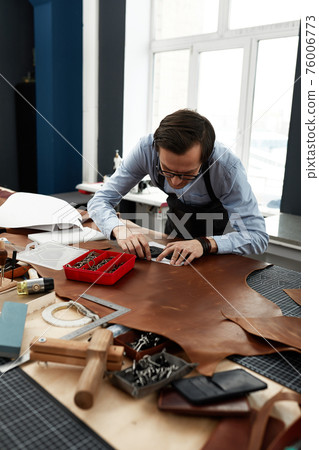 Skilled leather manufacture worker cutting some samples 76006773