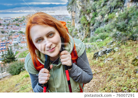 Young european woman with trekking poles against background of Lycian tomb and town of Fethiye in Turkey. 76007291