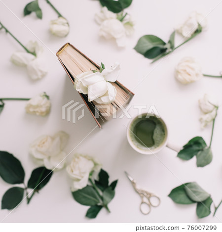A book with white roses and a cup of green tea on a white background, top view A book with white roses and a cup of green tea on a white background, top view 76007299