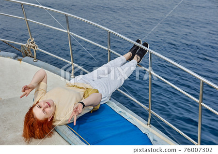 Beautiful Caucasian woman poses for photographer of lying on deck yacht for sightseeing tours. Beautiful Caucasian woman poses for photographer of lying on deck yacht for sightseeing tours. 76007302