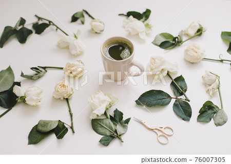 A cup of matcha tea and floral pattern with white roses on white background. Flatlay, top view, copy space 76007305