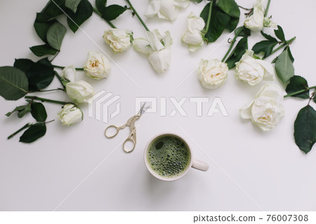 A cup of matcha tea and flowers on white table, view from above A cup of matcha tea and flowers on white table, view from above 76007308
