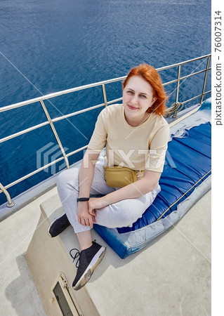 Pretty European woman poses for photographer on board yacht for sightseeing tours. Pretty European woman poses for photographer on board yacht for sightseeing tours. 76007314