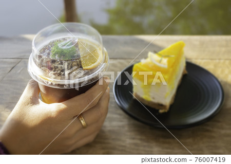 Holding a glass of iced coffee Holding a glass of iced coffee 76007419
