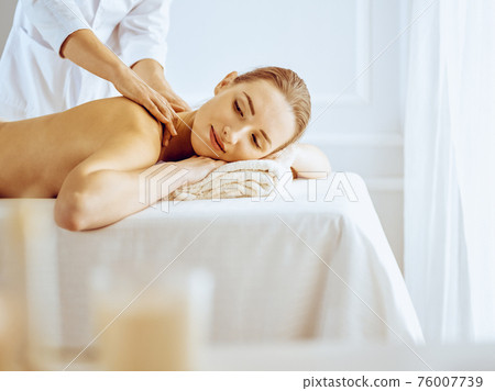 Beautiful woman enjoying back massage with closed eyes. Spa treatment concept Beautiful woman enjoying back massage with closed eyes. Spa treatment concept 76007739