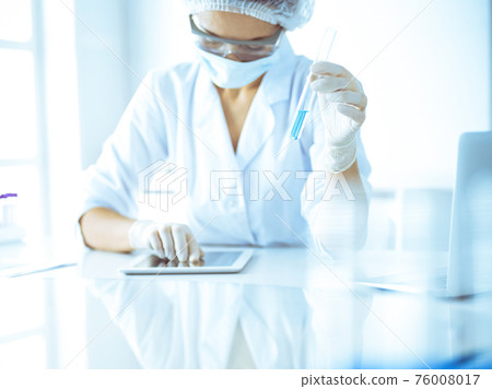 Professional female scientist in protective eyeglasses researching tube with reagents in laboratory. Concepts of medicine and research 76008017